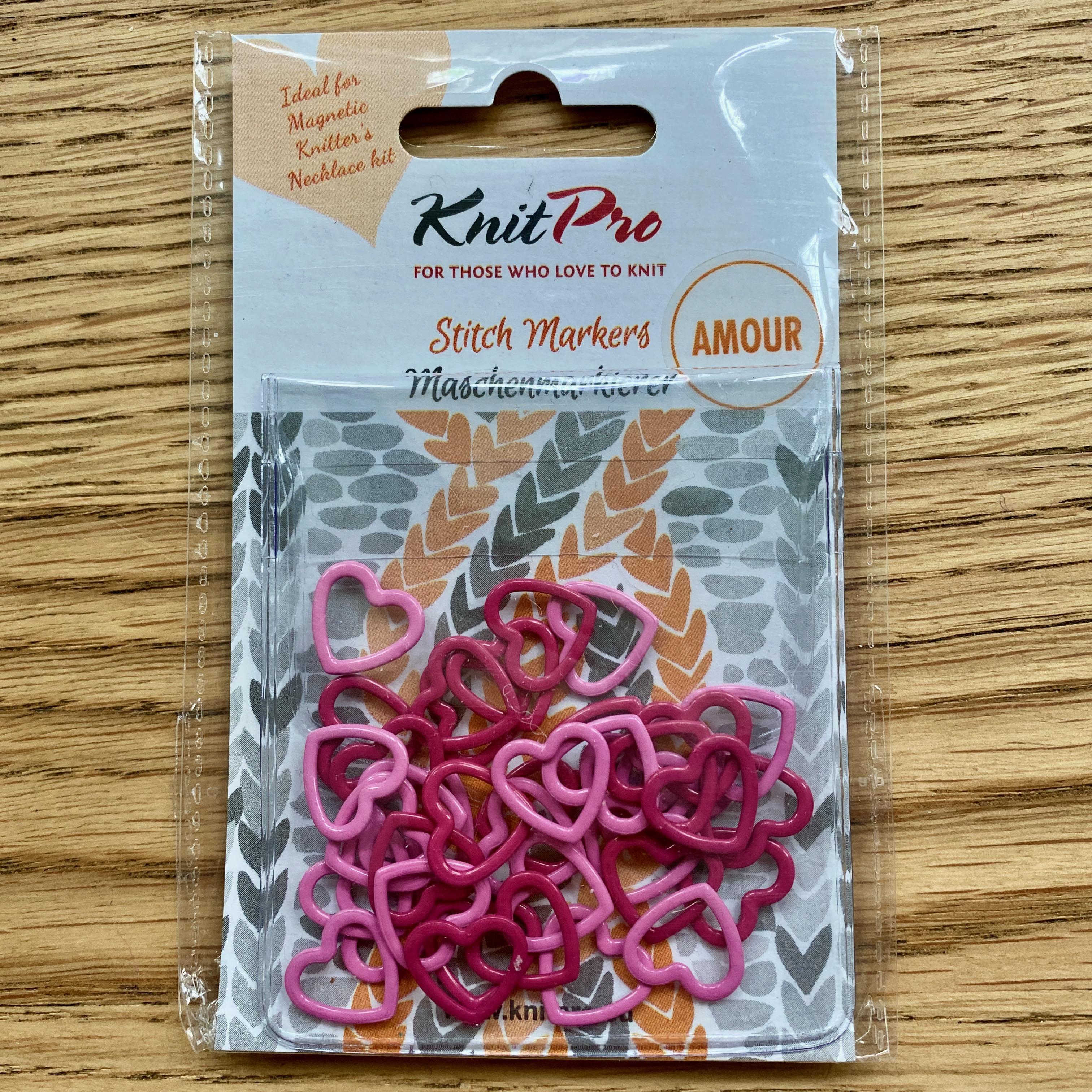 Pink heart stitch markers in plastic packaging on wooden table