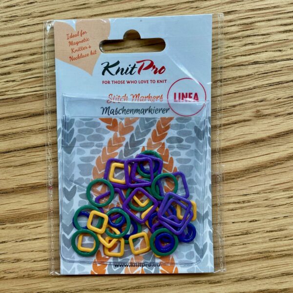 colourful metal stitch markers in plastic packaging on wooden table
