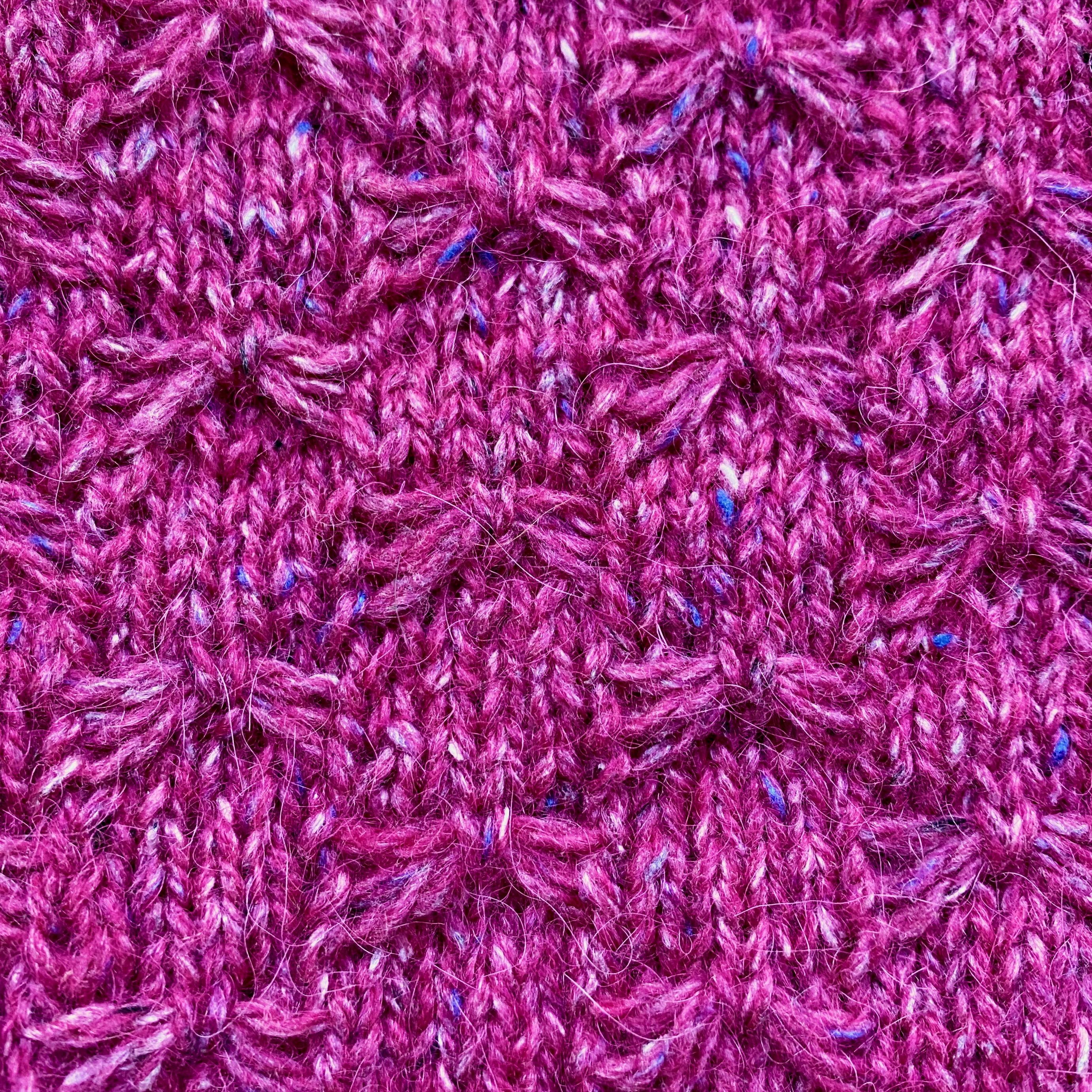 Close-up of butterfly stitch knitted with pink yarn - slipped stitches caught in the middle with holding stitch